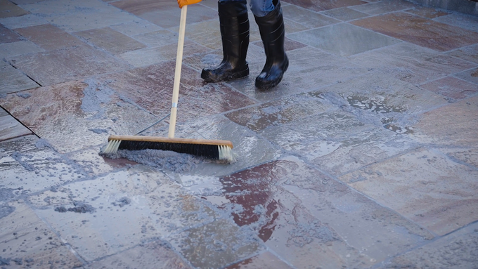 Contractor brushes resin grout into joints